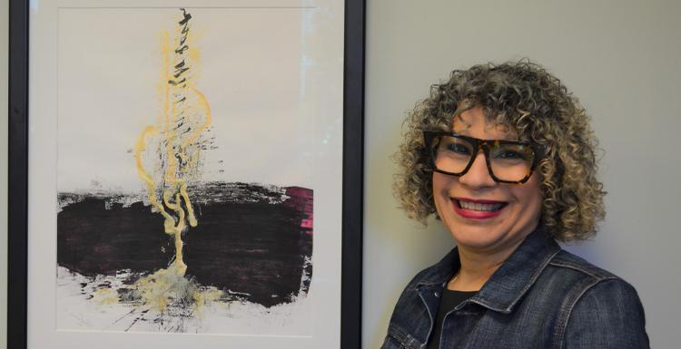 Dr. Alma Hoffman, 平面设计助理教授, 与她的画作“Micah 4”合影，这幅画被《十大彩票网投平台》评为2021年100件最佳艺术品之一. 